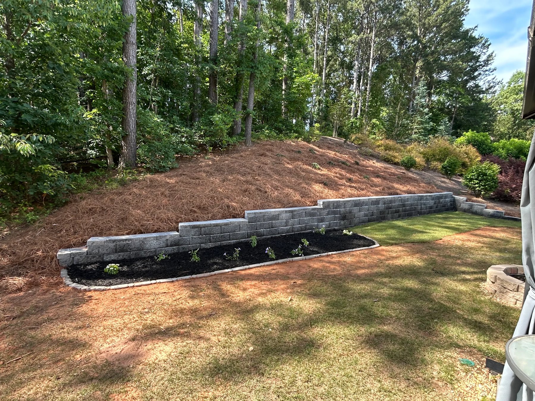 Landscaping project with retaining wall and pine straw